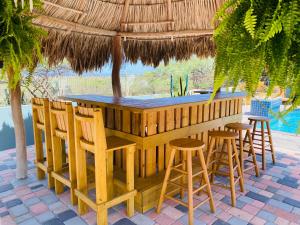 奥拉涅斯塔德La Felicidad Aruba的稻草伞下带凳子的木制酒吧
