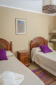 普尔马马尔卡Tierra Virgen Apartments的一间卧室配有两张带紫色枕头的床