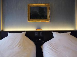 富士河口湖水之家酒店的卧室内配有两张白色的床,墙上挂着一幅画