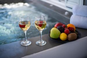 Éxo GoniáBlue Soul Luxury Villa的桌子上放着两杯葡萄酒和一盘水果
