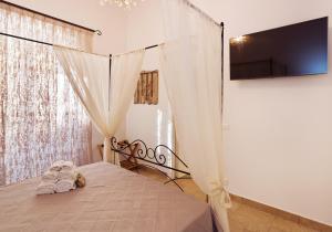 文蒂米利亚Casa Porta Marina的一间卧室配有一张带窗帘的床和一台电视