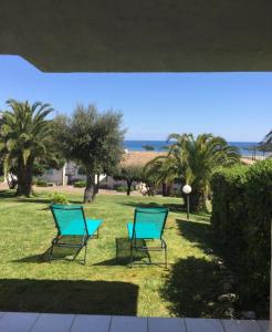 法沃内Favone Mini Villa Playa del Oro的两把蓝椅,在棕榈树园地