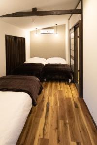 由布市Cominka Yufuin的卧室设有两张床,铺有木地板