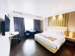 雅加达Orchardz Hotel Industri Jakarta Kemayoran的酒店客房设有一张大床和一张书桌。