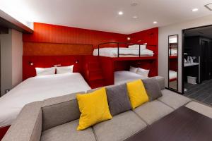名古屋GOLD STAY Nagoya Sakae ゴールドステイ名古屋栄的一间卧室设有两张床和一张带黄色枕头的沙发。