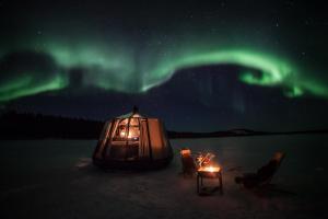 耶利瓦勒Laponia Sky Hut的帐篷配有椅子和桌子,位于北灯下