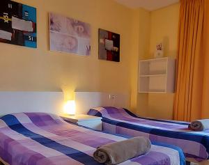 贝尼多姆Edificio Cadiz Benidorm的紫色和蓝色条纹间内的两张床