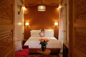 马拉喀什Elegancia Riad Boutique & SPA的酒店客房,配有一张床和一张红色椅子