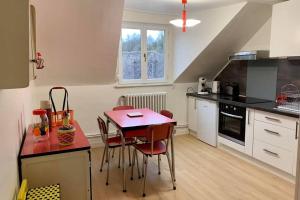 皮埃尔丰Appartement Vintage avec vue sur le château的厨房配有红色的桌子和椅子