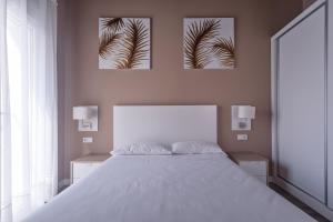 瓦伦西亚San Miguel, Luxury apartments.的卧室配有一张白色床,墙上挂有三张照片