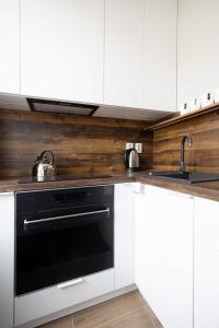 罗兹Royal Aparthotel Piotrkowska 33的厨房配有白色橱柜和黑烤箱。