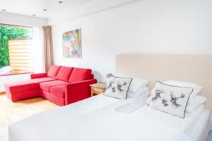 LavikLavik Fjord Hotel & Apartments的一间设有床铺和红色沙发的房间