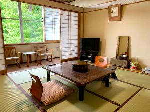 草津桐岛屋旅馆的客厅配有桌椅和电视。