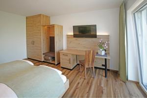 Sankt PeterGasthof Berger的一间带书桌的卧室以及一间带床和电视的卧室