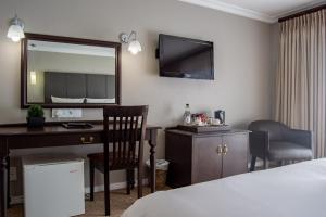 德班维尔Ruslamere Hotel and Conference Centre的酒店客房配有书桌和镜子