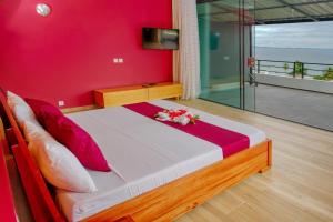 阿姆巴托洛阿卡Hôtel Villa Les Orchidées的一间卧室配有一张红色墙壁的床