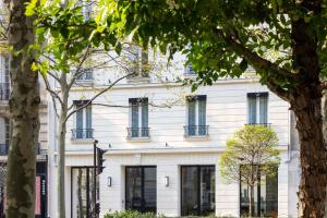 塞纳河畔讷伊Hotel Le 37 Bis的白色的建筑,设有窗户和树木