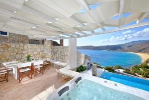 埃利亚海滩Luxurious Villa Ostria的户外庭院设有热水浴池和桌椅。