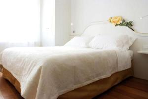 科内利亚诺Locanda Mezzosale的一张白色的床,上面有花