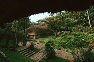 提喀迪Spice Village Thekkady - CGH Earth的花园中带茅草屋顶的房子