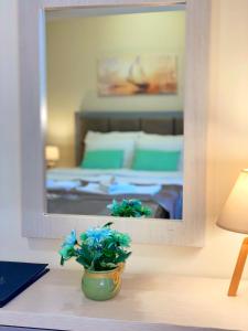 赫尔采格诺维Hotel Olimpija plus的一间带镜子的卧室和一个带蓝色花卉的花瓶