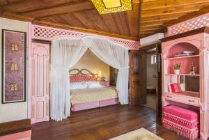 奥塔希萨尔Cappadocia Fairy Chimneys Minia Cave Hotel的一间卧室配有一张粉红色的床和天蓬