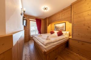 科尔蒂纳丹佩佐Cadin Apartment的卧室配有一张床铺,位于带木墙的房间内
