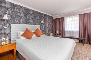 皇家滕布里奇韦尔斯顿桥威尔斯美居酒店的酒店客房配有一张带橙色枕头的大床