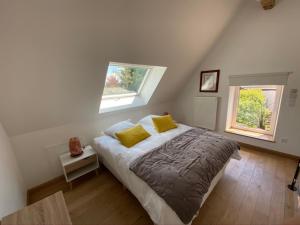 谢韦尔尼LA DEMALERIE的一间卧室配有一张带黄色枕头的床和两个窗户。