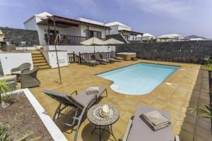 普拉亚布兰卡Villa Azure - LH122 By Villas Now Ltd的一个带游泳池、椅子和房子的庭院