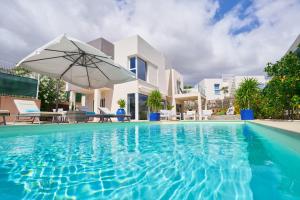 帕莱索海滩Villa Flamencos Rosas, Costa Adeje的一个带遮阳伞和房子的游泳池