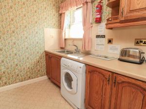 伍勒Blueberry Cottage的厨房配有洗衣机和水槽