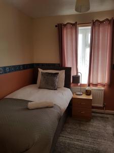 梅德斯通Delight Marvel-Derby House at Maidstone的一间卧室配有床和一个带粉红色窗帘的窗户。