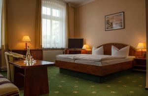 塞巴特阿尔贝克Hotel Meereswelle - Anno 1875的一间卧室配有一张床、一张桌子和一台电视。