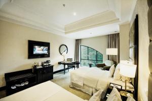 万隆帕班达烟酒店的大型酒店客房,配有一张床和一张书桌