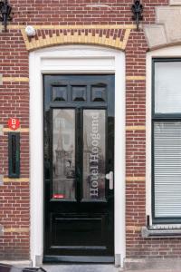 斯内克Stadslogement Hoogend的砖砌建筑中一扇带标志的黑色门