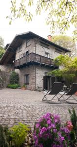 波里奥特米Casa Vacanza Scacco d' Argento的一座石头建筑,配有两把椅子和阳台