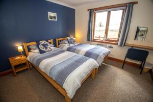 托伯莫里阿尔勒旅舍的配有两张床铺的蓝色墙壁和窗户