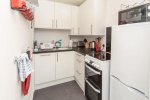蒂恩格Rona@Knock View Apartments, Sleat, Isle of Skye的厨房配有白色橱柜和冰箱。