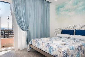 加埃塔Acquazzurra Gaeta的一间卧室配有一张带蓝色窗帘的床和一扇窗户