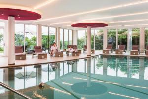 罗特翁特尔里特堡阿尔特瑞比斯查勒霍弗酒店的一座游泳池,里面的椅子上坐着
