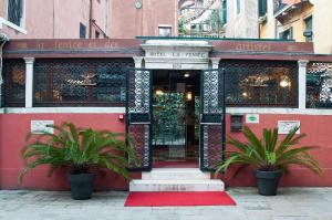 威尼斯艾狄阿堤丝泰斯菲尼斯酒店的前面有两株植物的红色建筑