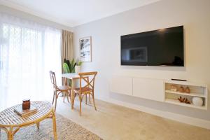 黄金海岸棕榈湾酒店的客厅配有桌子和墙上的电视