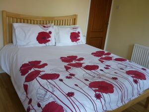 汉普顿茵雅顿Gayton Bed & Breakfast的白色棉被上带红色鲜花的床