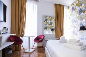 罗马新昆塔特雷酒店的酒店客房,配有一张床和两张红色椅子