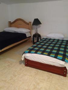 贾丁Hostal Naty Luna的一间铺有瓷砖地板的卧室,配有两张床和一盏灯。