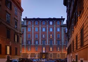罗马圣彼得精品客房旅馆的一座大型砖砌建筑,前面有汽车停放