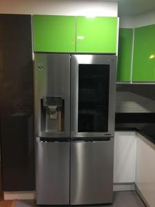 基多Misuitehotel La Carolina Quito的一个带绿色橱柜的厨房里的不锈钢冰箱