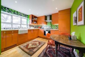 伦敦3 bedroom Apartment on Portobello Road in Notting Hill的厨房拥有橙色和绿色的墙壁,配有木桌