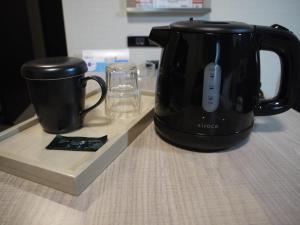 米子市Hotel Route-Inn Yonago的黑色咖啡壶和柜台上的杯子